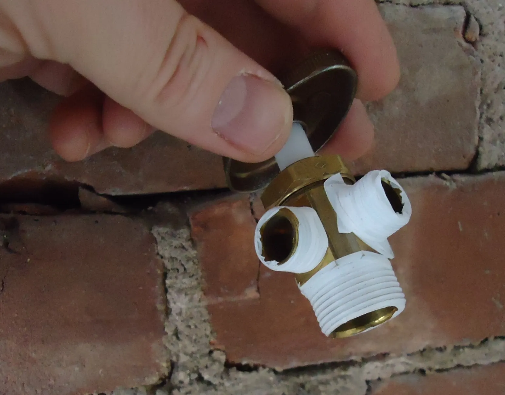 Plumber sealing a brass shut off valve with thread tape